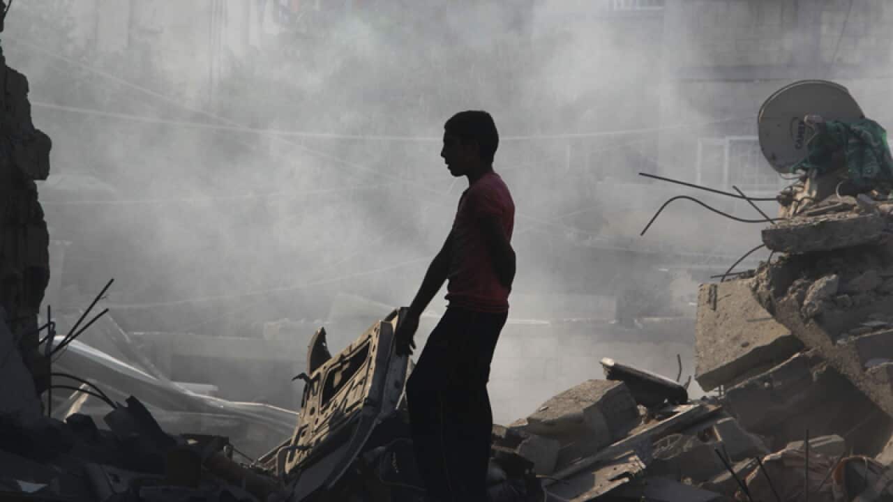 A Palestinian looks for belongs in the rubble of his house.