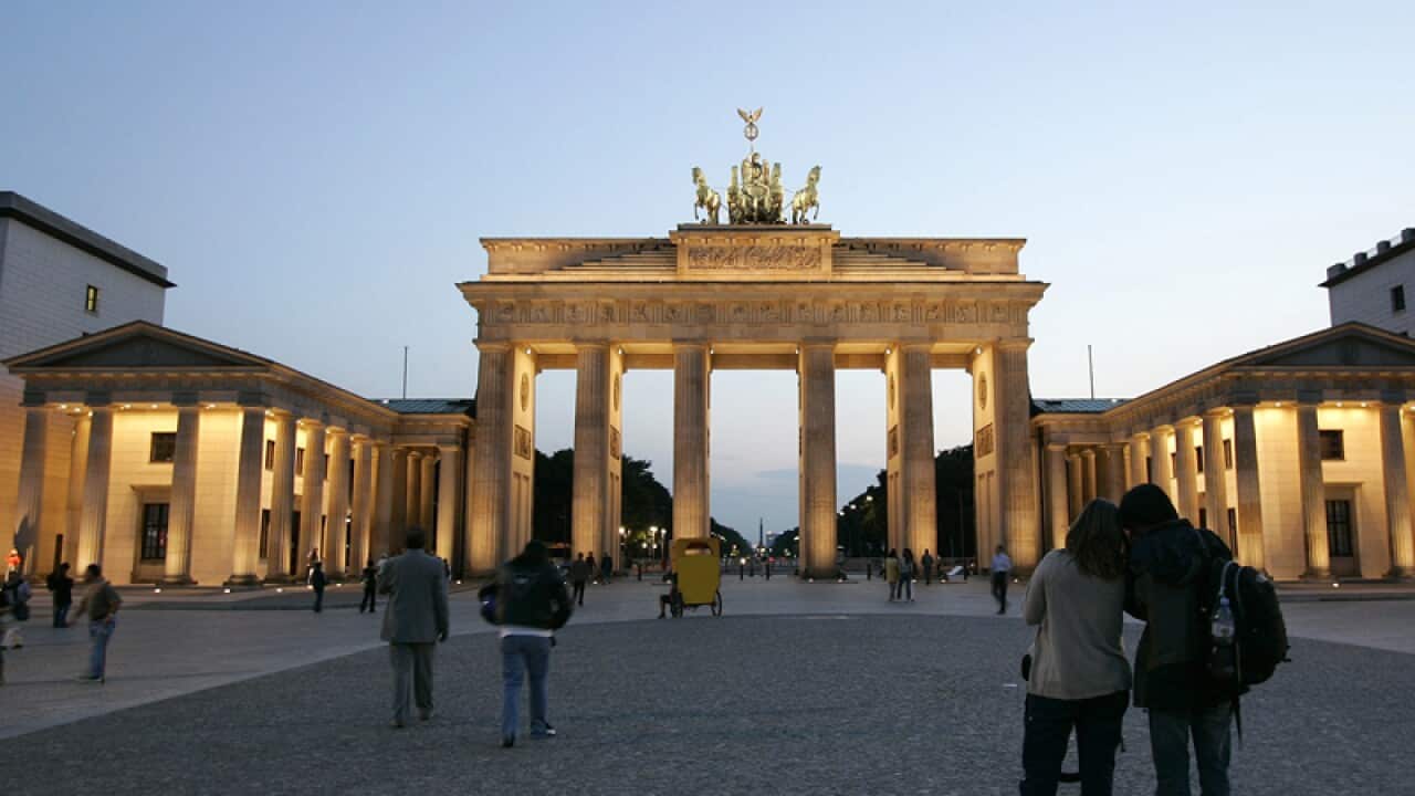 Tourists stroll in front of the Brandenburg Gate in Berlin.