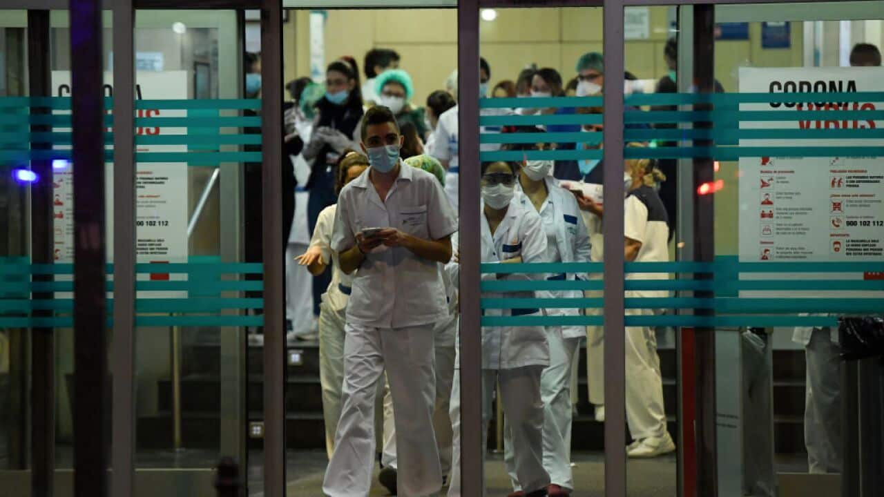 Healthcare workers dealing with the new coronavirus crisis stand at the entrance of the Fundacion Jimenez Diaz hospital in Madrid