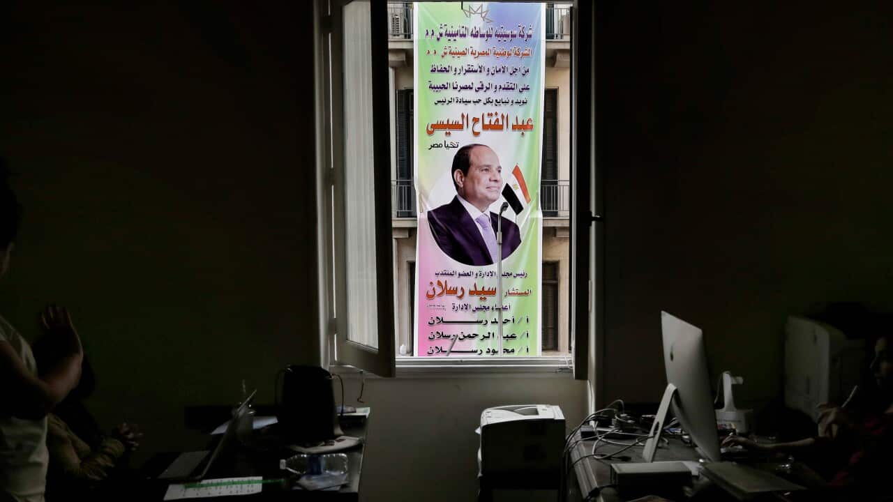 staff working for the Downtown Contemporary Arts Festival work as an election campaign banner hangs on a building in front of them, in Cairo.