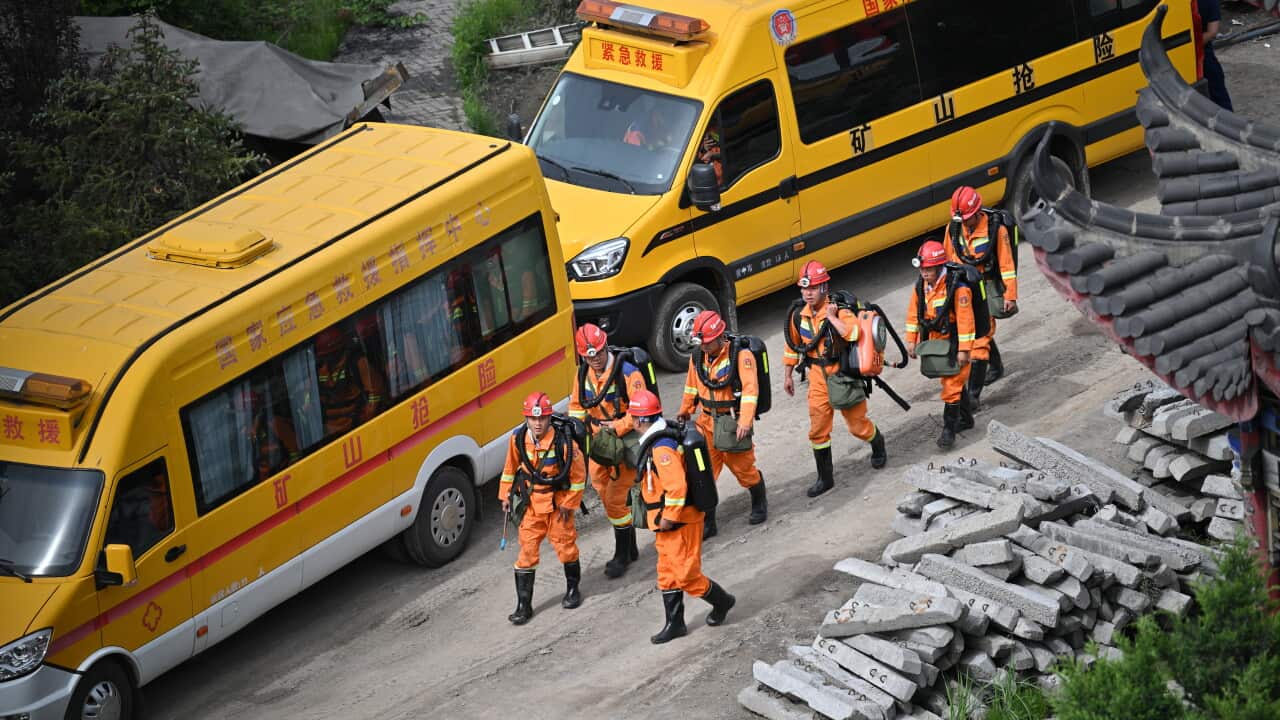 Rescue workers wearing orange suits near an accident site with two vechiles beside them