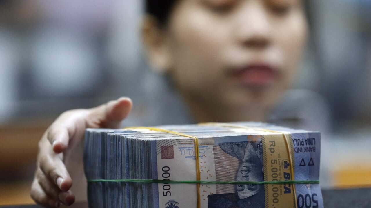 An Indonesian employee prepares rupiah banknotes at a money changer in Jakarta, Indonesia,