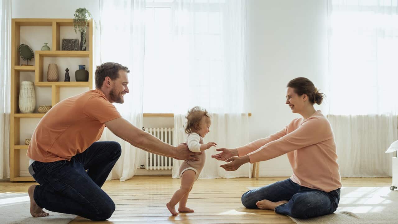 Parents helping daughter walking at home