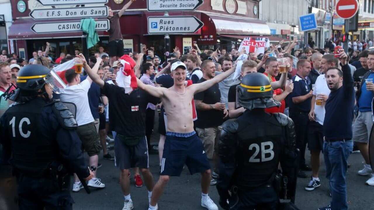 Riot police monitor England fans outside the train station in Lille city centre
