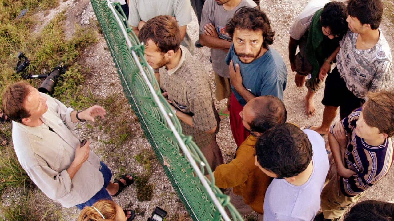 Refugees gather on one side of a fence to talk with international journalists about their journey that brought them to the Island of Nauru.