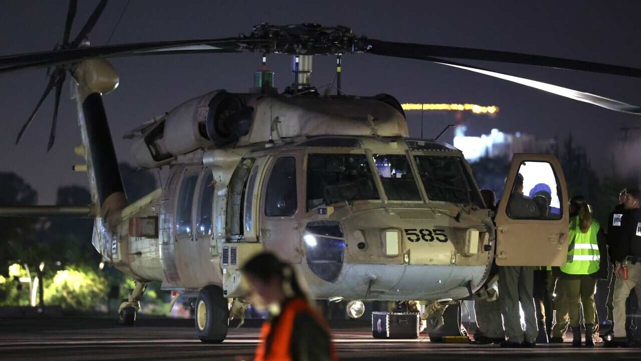 Staff stand near a helicopter on the tarmac.