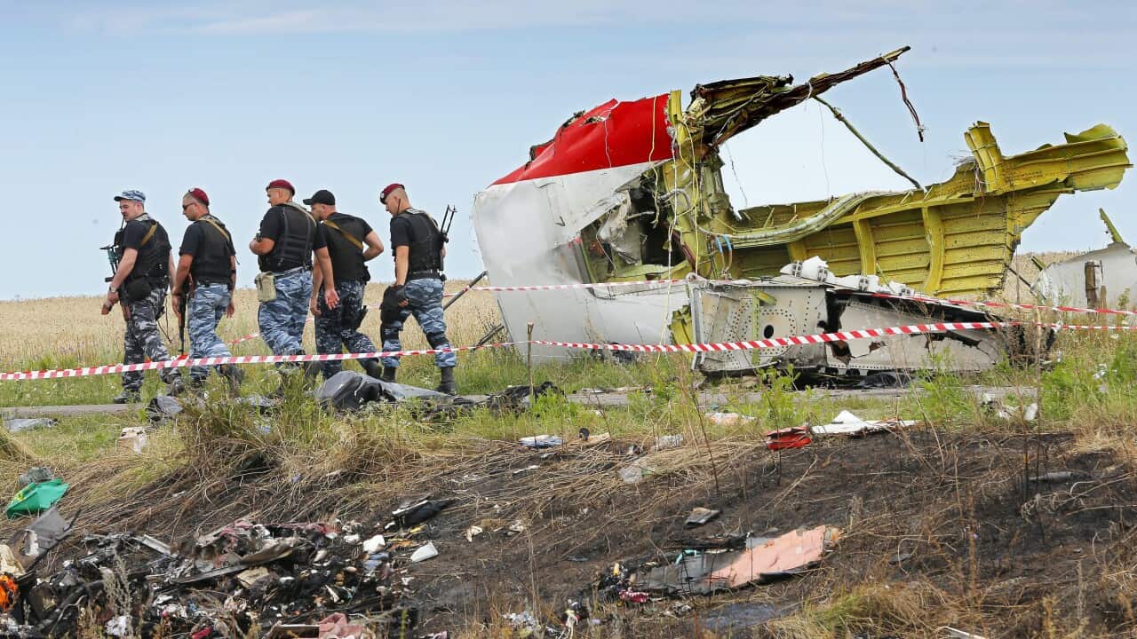 File photo dated 20 July 2014 showing armed rebel soldiers passing a big piece of debris at the main crash site of the Boeing 777 Malaysia Airlines flight MH17