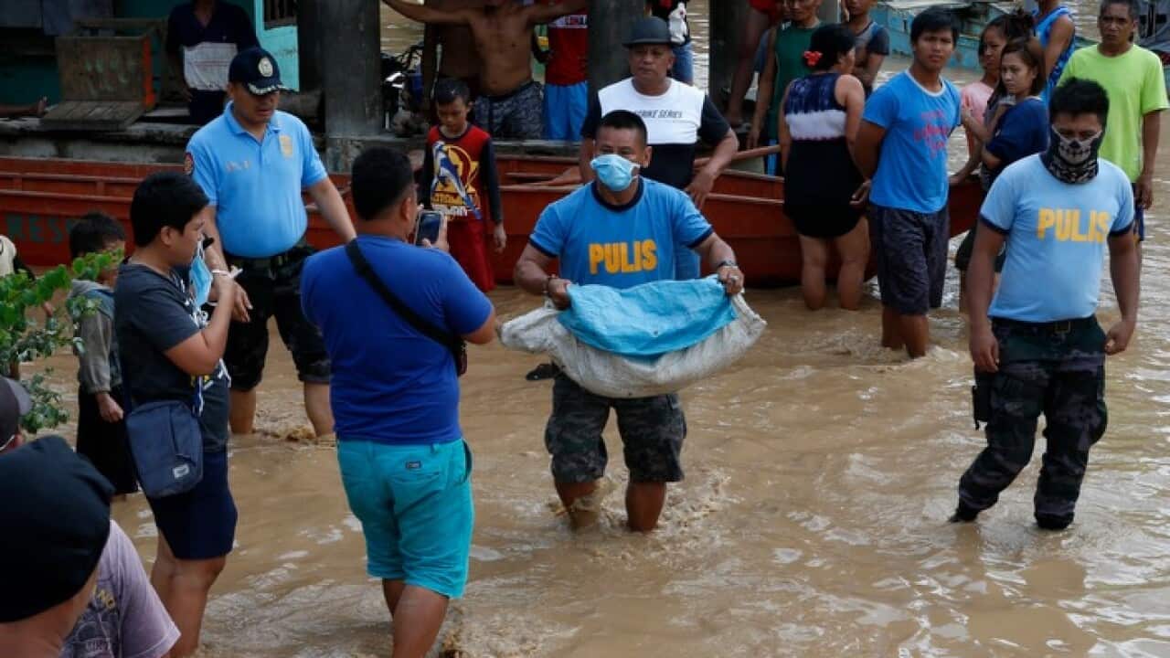 A Filipino policeman walks through floodwaters in the town of Salvador, Lanao del Norte province, Philippines, 23 December 2017.
