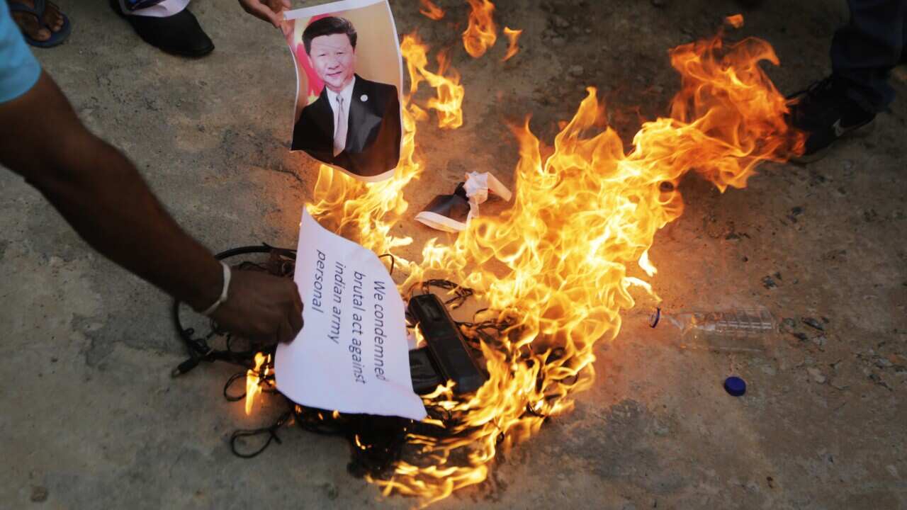 An Indian man burns a photograph of Chinese president Xi Jinping during a protest against China in Ahmedabad, India.