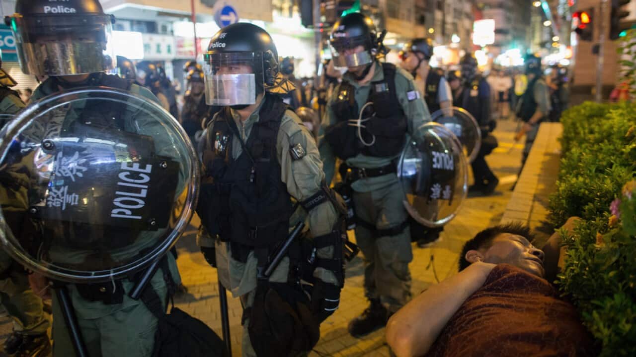 A man sleeps in the park as anti-riot police conduct a clearing operation in Mongkok, Hong Kong.