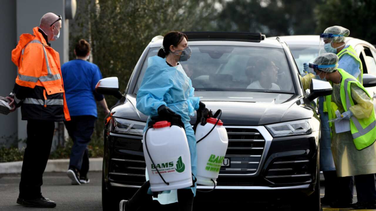A cleaner dressed in Personal Protective Equipment (PPE) is seen leaving the Crossroads Hotel in Sydney, Saturday, July 11, 2020