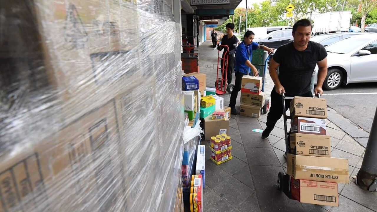 Employees of an IGA supermarket are seen unpacking stock outside their store in North Melbourne, Wednesday, March 18, 2020.