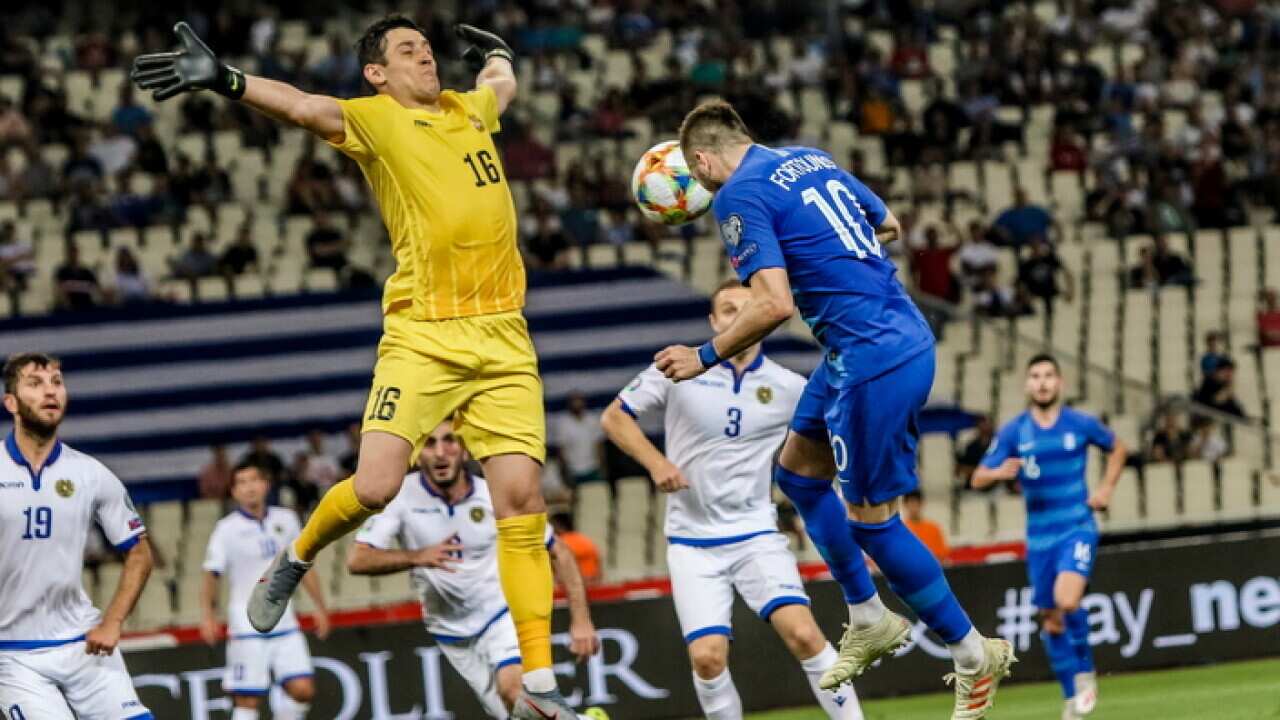 Greece's Kostas Fortounis (R) vies for the ball with Armenia’s goalkeeper Aram Airapetyan.