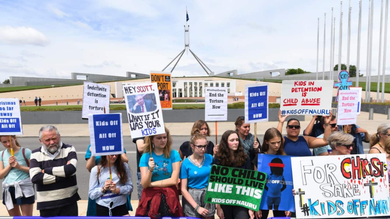 Protesters hold up signs during a rally demanding the resettlement of kids held on Nauru outside Parliament House in Canberra, Tuesday, November 27, 2018. (AAP Image/Lukas Coch) NO ARCHIVING