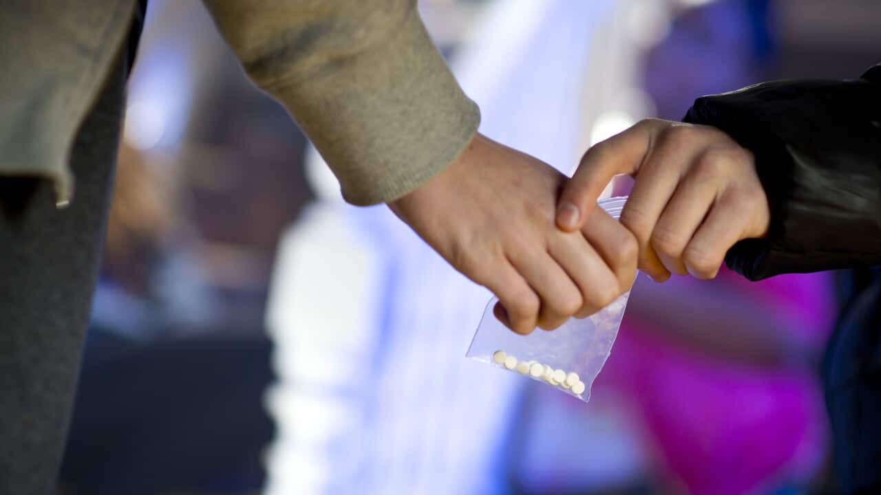 Hands passing over a bag of pills