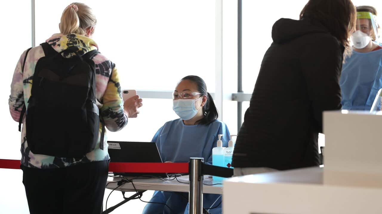 Health Care workers are seen checking passengers arriving from Sydney at Perth Airport