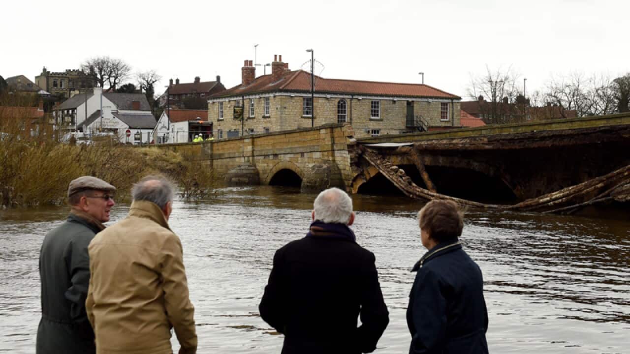Locals look at a bridge that collapsed following recent flooding