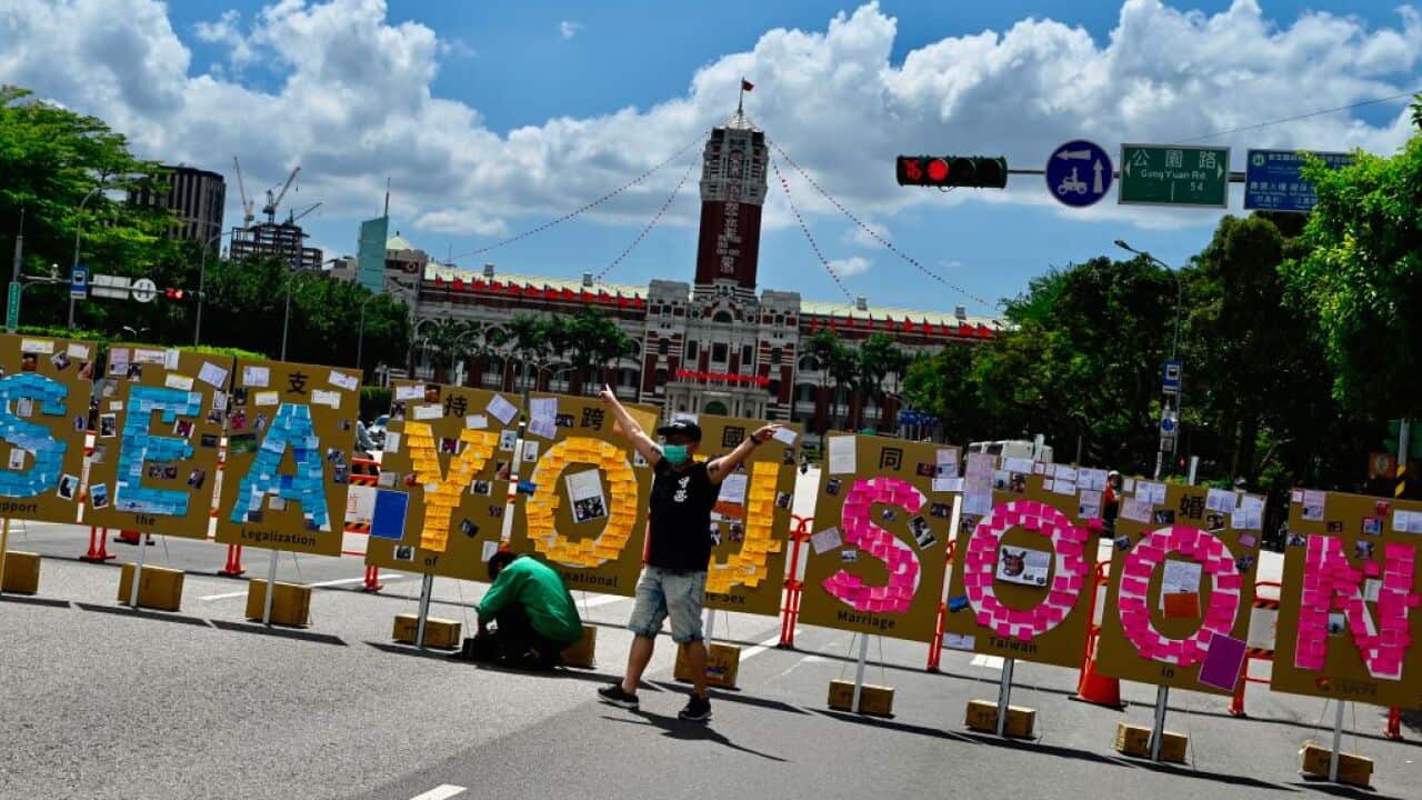 A man poses for photos in front of a 'Lennon Wall' in Taipei on May 17, 2020.