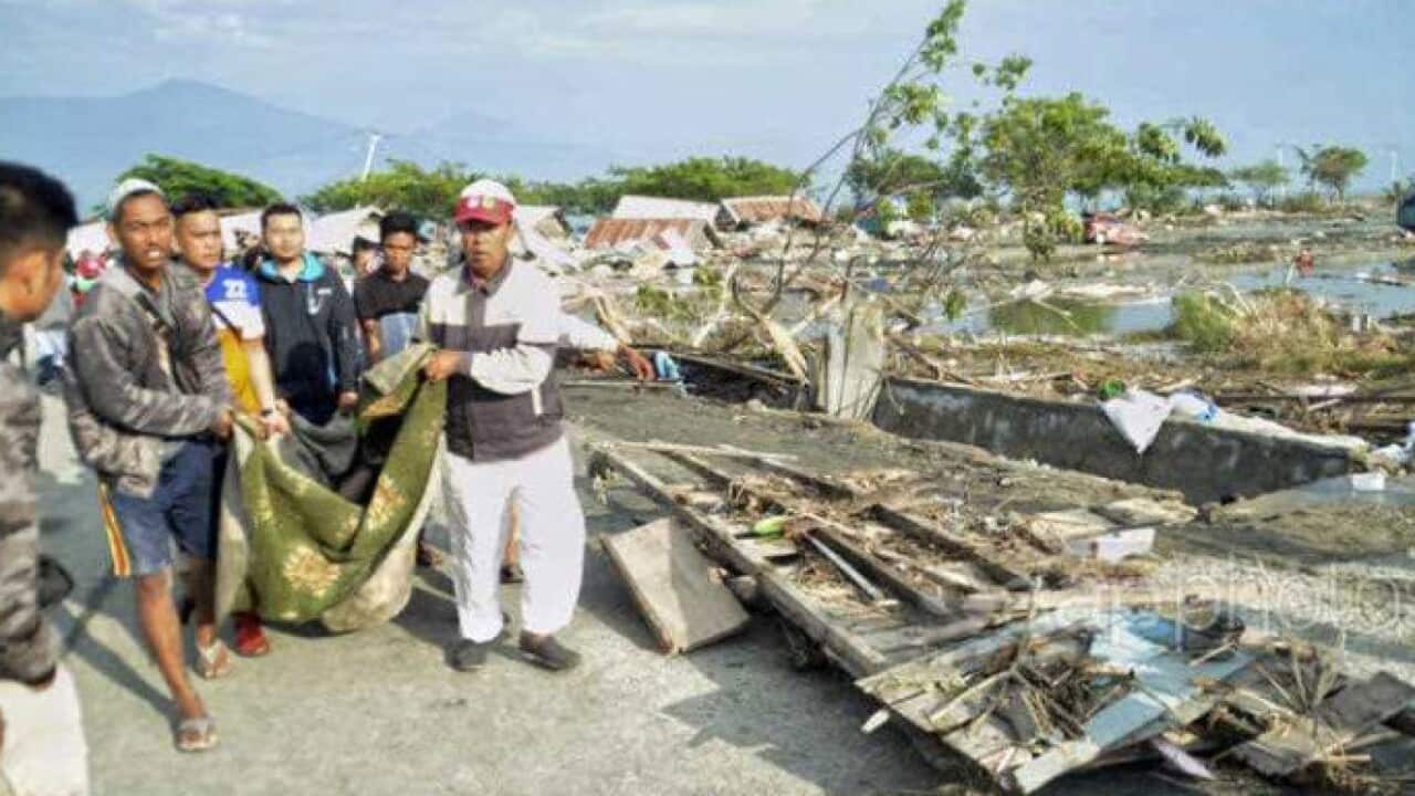 People carry the body of a tsunami victim in Palu, Indonesia