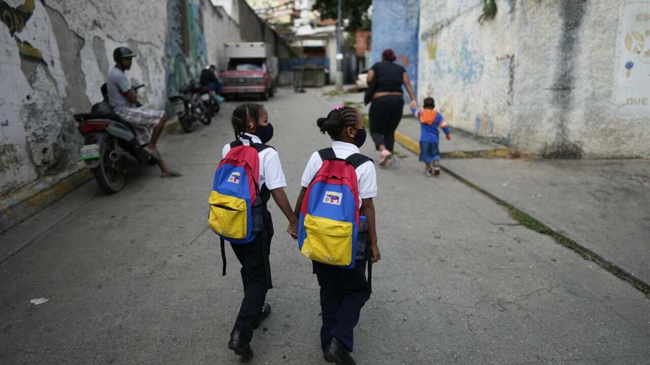 Girls walk to school on the first day back to in-person classes since the start of COVID-19 pandemic restrictions in Venezuela.