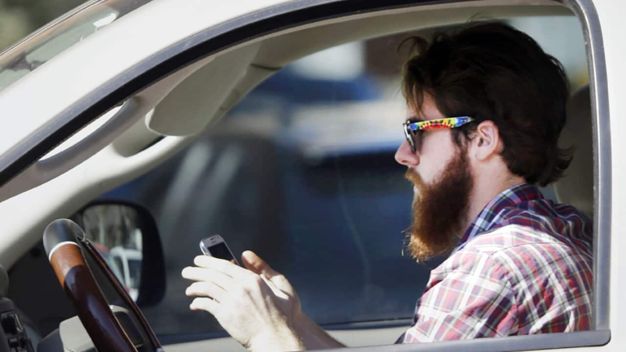 A man uses his cell phone as he drives through traffic in Dallas