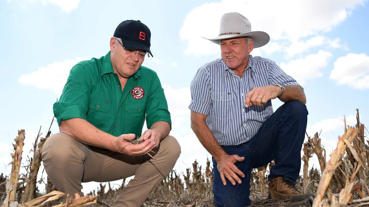 Prime Minister Scott Morrison (left) inspects the dry soil with farmer David Gooding on his drought-affected property near Dalby, Queensland.