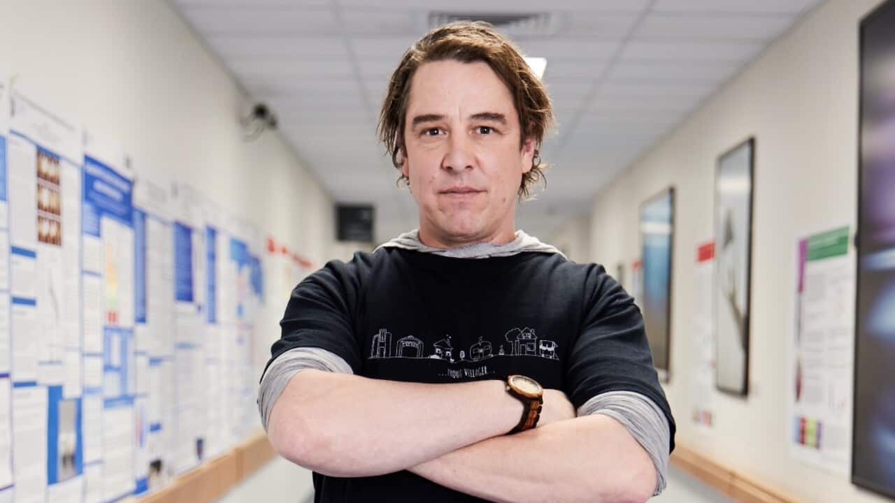 A man stands in a hospital corridor.