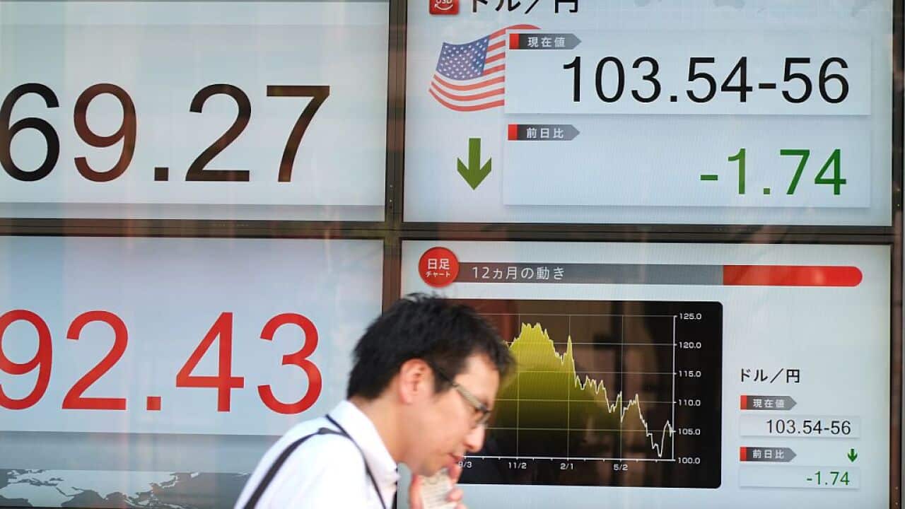 A pedestrian walks past an electric quotation board displaying the rate of the Japanese yen against the US dollar.