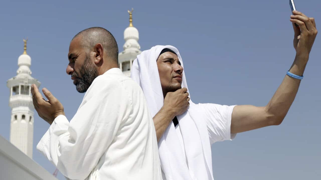 A Muslim pilgrim prays as another takes a photo with his mobile phone at the Grand Mosque in the holy city of Mecca.
