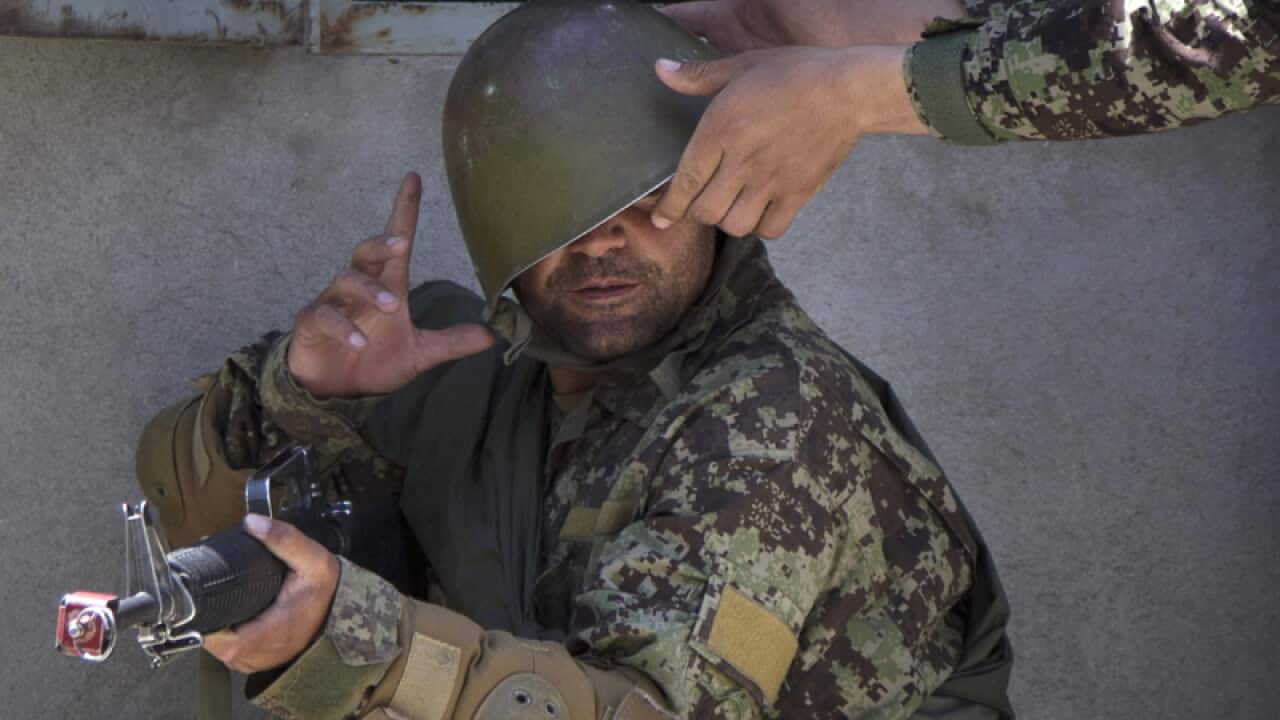 Afghan troop struggles with his helmet