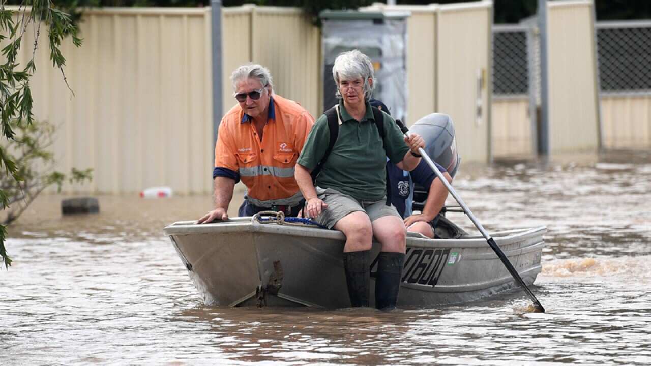 A couple steer their boat through flooded streets in Rockhampton