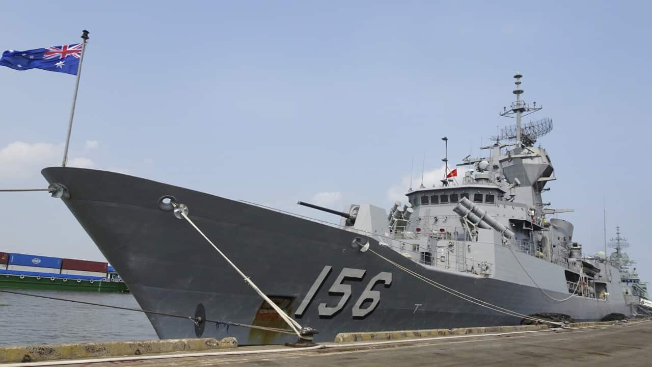 Large grey navy ship docked at a port