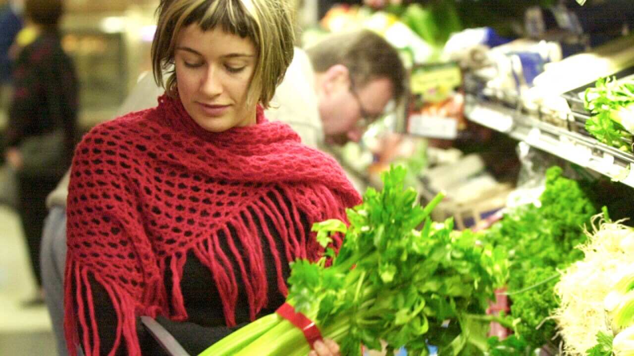 A woman chooses to buy celery at a supermarket.