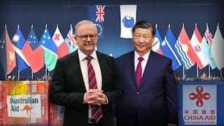 A composite graphic featuring Australian Prime Minister Anthony Albanese and Chinese President Xi Jinping standing in front of Pacific island nation flags, flanked by "Australian Aid" and "China Aid" logos.