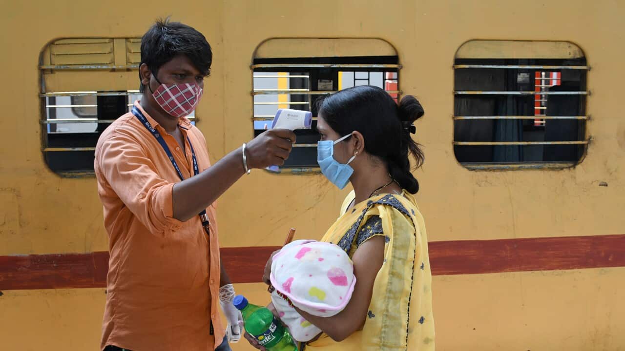 A woman carrying a baby is screened for temperature on arrival by train at Dadar Terminus, Mumbai, the capital of the hardest-hit state Maharashtra.