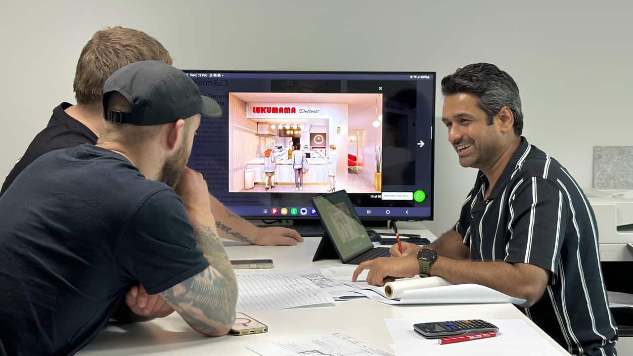 picture of three men working on a design map on a table