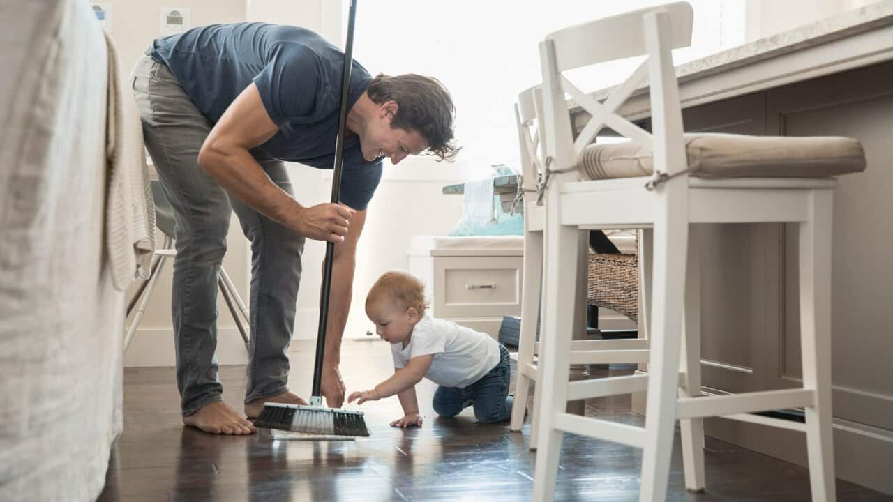 Baby son watching father sweeping floor