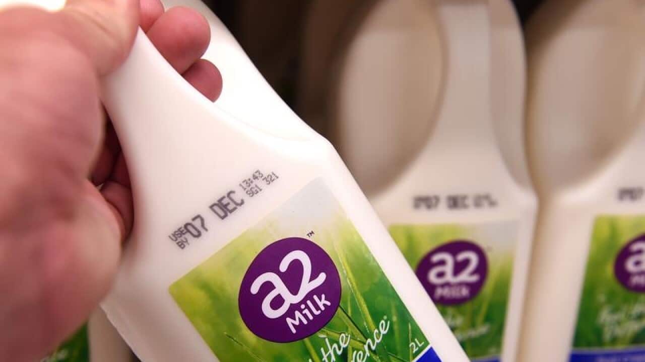 Bottles of A2 milk is held in front of others.