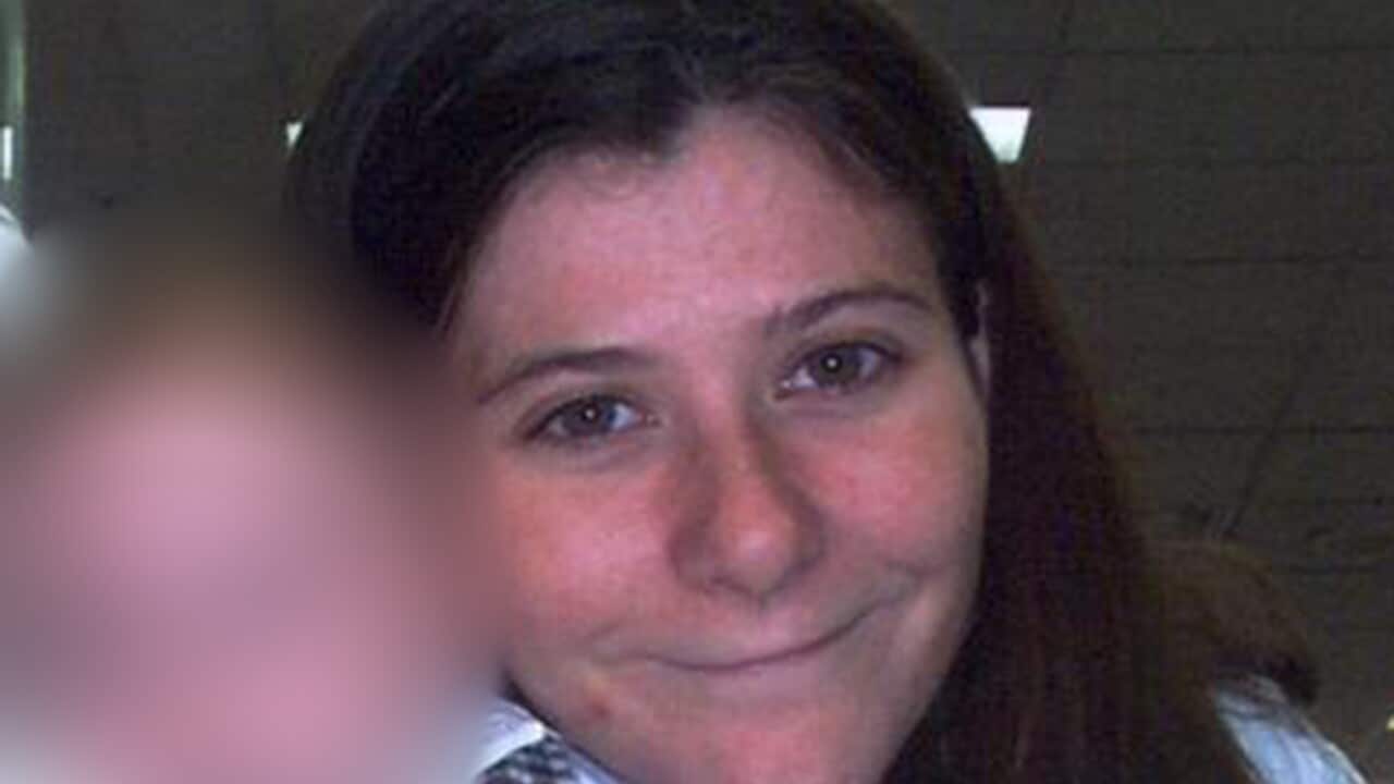 A young woman with brown hair holding a baby. The baby's face is blurred.