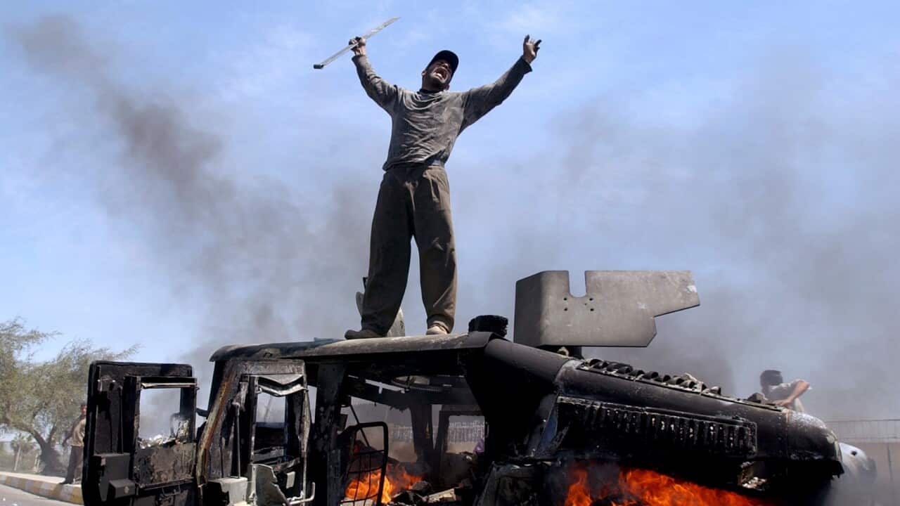 An Iraqi man celebrates atop a burning US Army Humvee in the northern part of Baghdad, Iraq, in 2004 (AAP).