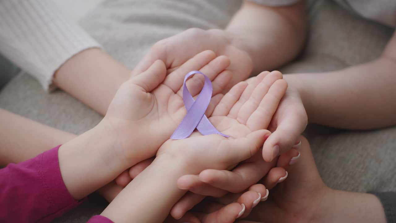 A child's hands holding the purple ribbon signifying domestic violence awareness (Getty)