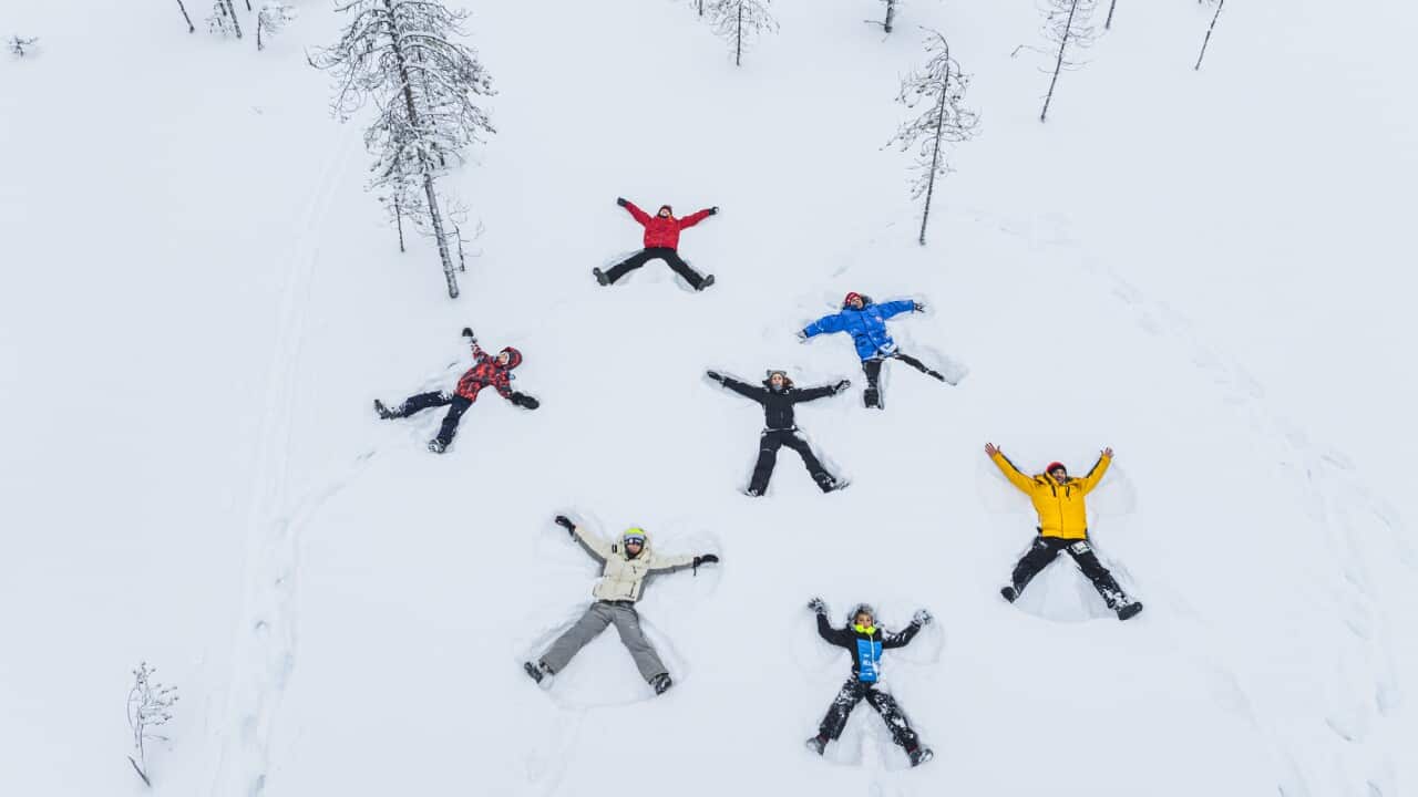 Tourists having fun lying down in the snow, overhead view