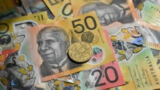 A selection of Australian bank notes and coins laid out in a pile.