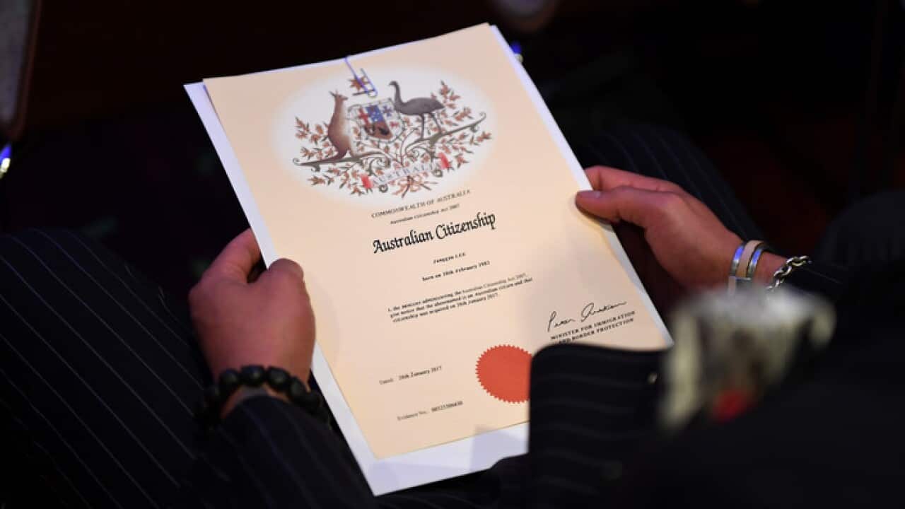 An Australian citizenship recipient holds his certificate during a citizenship ceremony on Australia Day in Brisbane
