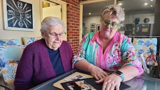 Two women looking at a photo album on a glass table
