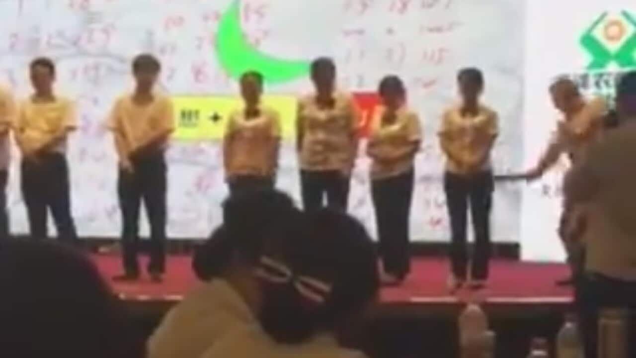Screenshot from the video showing a man spanking his employees with a paddle 