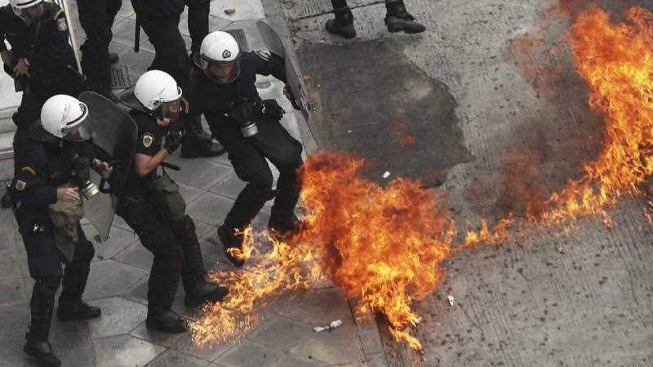 Riot police officers try to avoid a patrol bomb thrown by protester during a nationwide general strike demonstration. in Athens