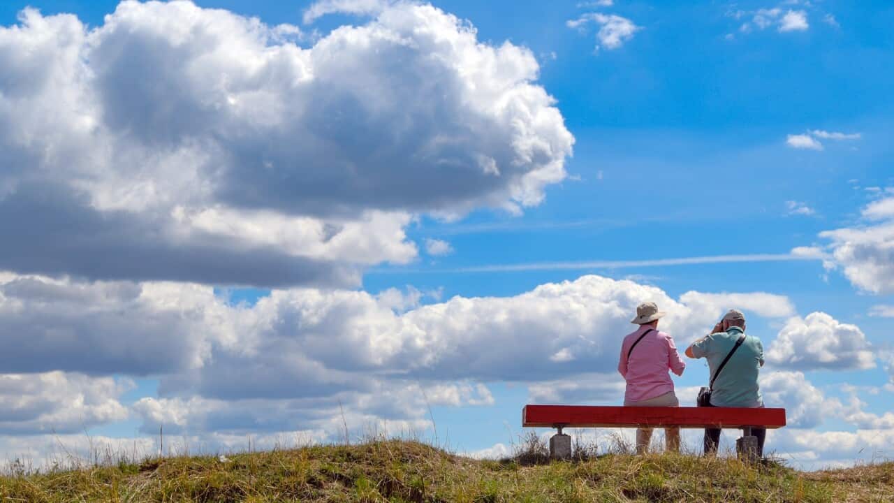 Two people sitting on a hilltop bench