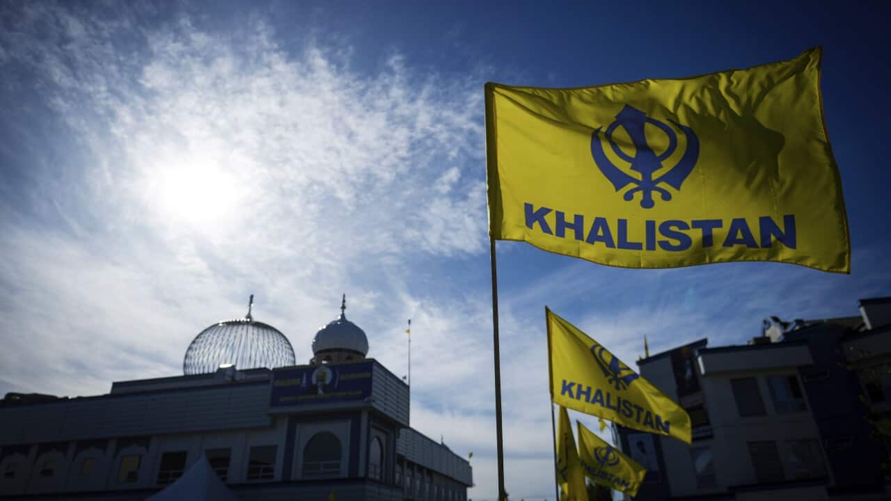 Yellow and blue Khalistan flags fly outside a temple
