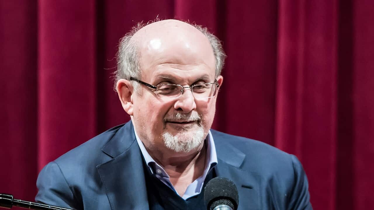 Salman Rushdie speaking into a microphone